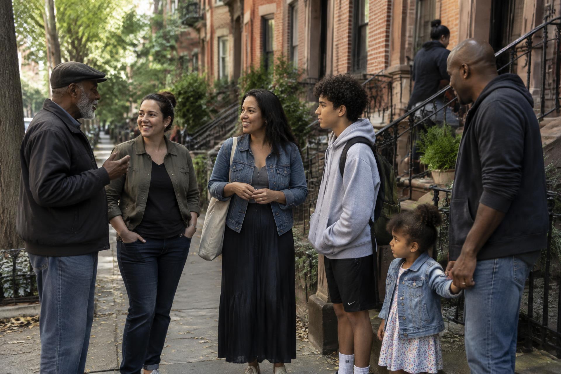 A group of New Yorkers of all ages standing together on a neighborhood street